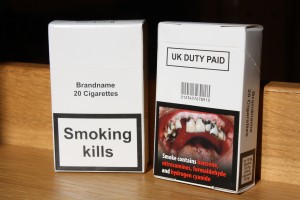 Pic of cigarette box with plain packaging labels on it. "Smoking Kills", and pic of cancerous mouth. 