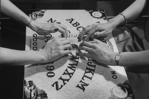 People playing with a Ouija Board.  (Pho