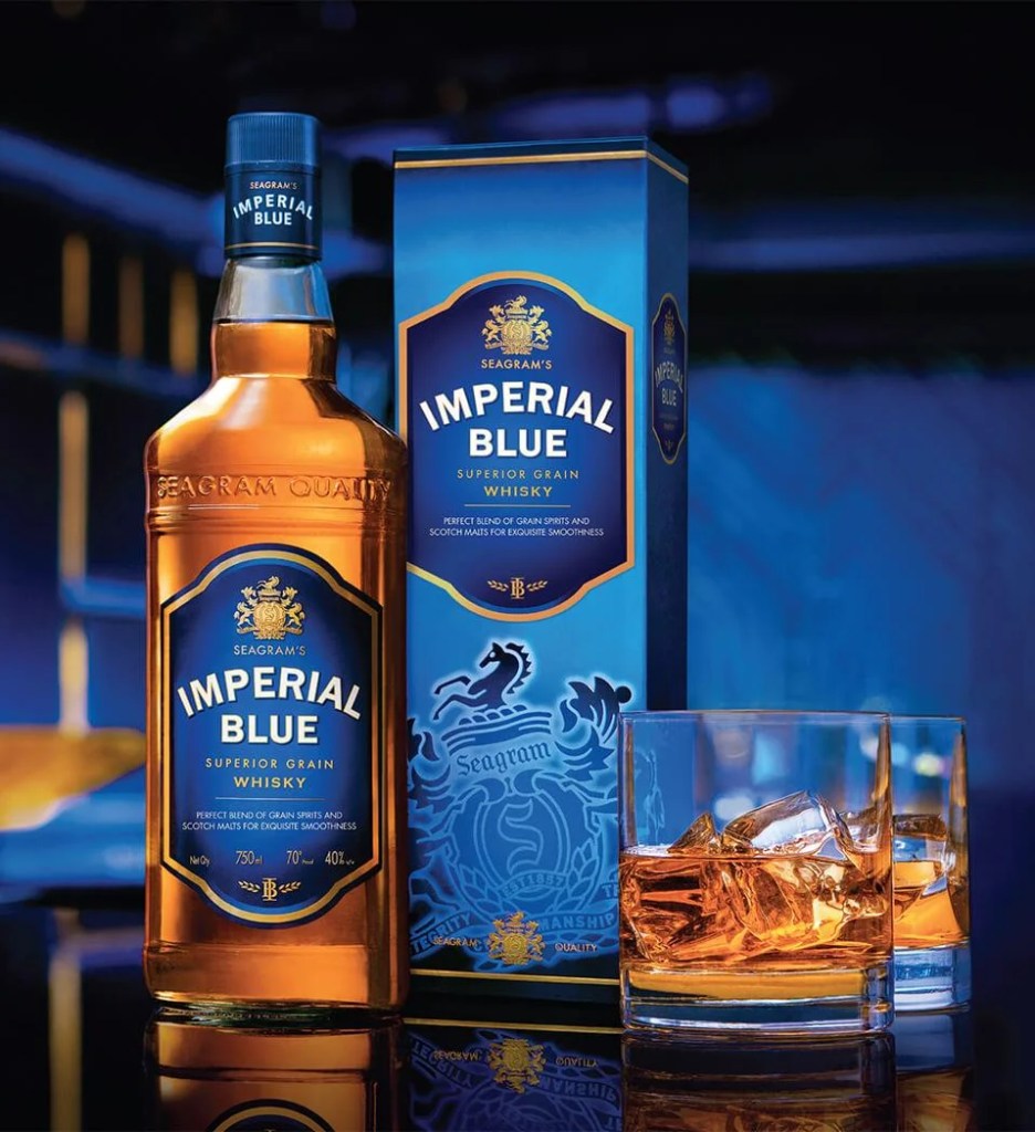 Imperial Blue whiskey bottle along with the packaging material and a filled glass of whiskey with ice cubes. 